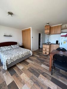 a bedroom with a bed and a table and a kitchen at Apartamento cerca de Casino Marina del Sol en Talcahuano in Talcahuano +2 photos