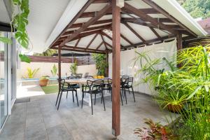 Un patio con una pérgola de madera con mesa y sillas. en Tiaki Guesthouse Apartment - 5min drive to beach & Shops ! 1BDR APT with pool, en Punaauia