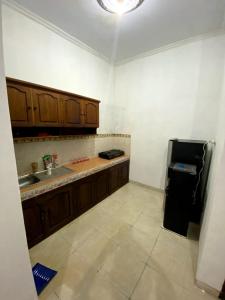 a kitchen with wooden cabinets and a black refrigerator at Cosinus Purwosari in Kejayan