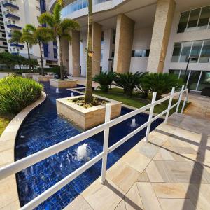 a white fence in front of a building with a fountain at Encontro marcado in Praia Grande