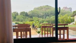 a room with two chairs and a view of a field at Sigiri Rock View Lodge in Sigiriya