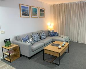 ein Wohnzimmer mit Sofa und Tisch in der Unterkunft Corrigans Beach View Apartment 211 in Batehaven