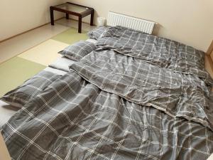 Una cama con una manta encima en un dormitorio. en ふでのや, en Wada