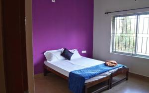 a bedroom with a bed with a purple wall at Green Echoes by Tripture - Holiday Villas in Coorg in Cherambane