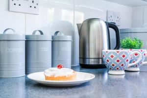 a table with a pastry on a plate and a cup of coffee at Monmouth House Aylesbury Premier Quality Accommodation For Larger Families Contractors And Professionals Sleeps Up to 6 Guests in Buckinghamshire