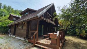 a wooden cabin with a porch and a deck at 自然豊かな森の中に静かに佇むログハウス #貸別荘 #一棟貸切 #グループ旅行や家族旅行におすすめ #広々吹き抜けリビング #BBQのできるウッドデッキ #ジブリ風空間 #満天の星空 #鋸南 #南房総 #komorebi in Kyonan