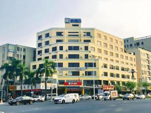 a large building with cars parked in a parking lot at PAI Hotel Zhuhai Doumen Daxin Xinduhui Bus Terminal in Zhuhai