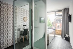 a glass shower door in a bathroom with a table at Stravinsky Slapen in Hengelo