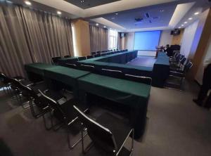 a conference room with green tables and chairs and a screen at Echarm Hotel Beijing Yizhuangrong Dongjie Metro in Beijing