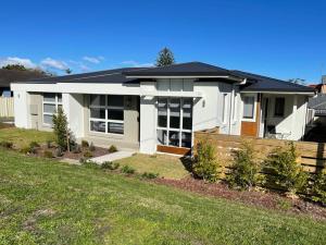 ein weißes Haus mit einem Zaun davor in der Unterkunft Brand new 5 star category home at RedHead beach in Redhead