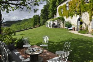 a patio with chairs and a table and a lawn at Gîtes Le Relais de Roquefereau in Penne-dʼAgenais