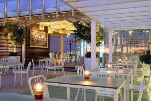 a patio with tables and white chairs and tables and tablesearcher at Gajahmada Avara Boutique Hotel in Pontianak