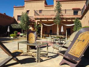 a patio with a table and chairs in front of a building at La Perle Du Dades in Boumalne