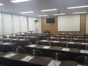 a conference room with tables and chairs and a screen at Jinjiang Metropolo Hotel Classiq Shanghai Off Bund in Shanghai