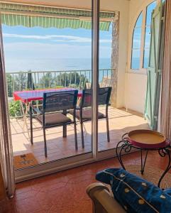a balcony with a table and a view of the ocean at Gîte "Villa SIMONE" Vue Mer 180° CALME Terrasse couverte Jardin. in Carqueiranne
