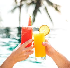two people holding up drinks in their hands near a pool at ALMOND Cove in Grand Case