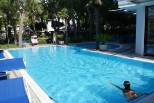 a man swimming in a large swimming pool at Hotel Sporting in San Benedetto del Tronto