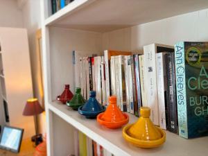 a shelf with colorful vases on it with books at Beldi chic & calme, patio végétalisé et terrasse in Essaouira
