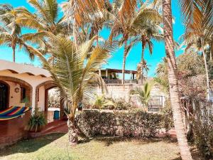 a house with palm trees in front of it at Beautiful Beach House in Lo De Marcos, Nayarit! in Lo de Marcos