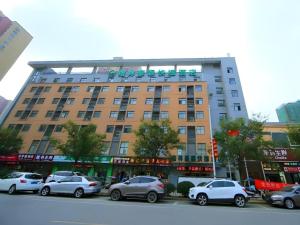 a large building with cars parked in a parking lot at GreenTree Inn Wuxi Huishan District Xizhang Metro Station Express Hotel in Wuxi