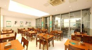 a restaurant with wooden tables and chairs and windows at GreenTree Inn Fujian Fuzhou Software Park River View Business Hotel in Fuzhou