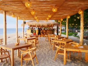 a restaurant on the beach with wooden tables and chairs at Jungle Gili Air in Gili Islands