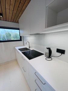 a white kitchen with a sink and a window at Kargevärava Elamustalu in Kapra