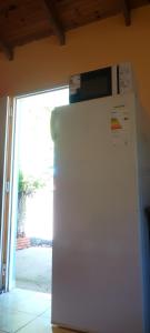 a white refrigerator with a microwave on top of it at La Gringa in Villa Elisa