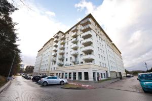 a large white building with cars parked in a parking lot at YOURAPART Gdansk Morena in Gdańsk