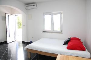 a white room with a bed with a red pillow on it at Villa Gorica Apartments Ražanj in Ražanj