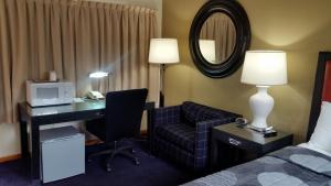 a hotel room with a desk and a bed and a mirror at The Simplicity Inn in Marshfield