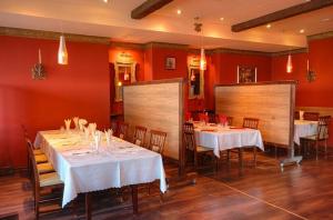 un restaurante con mesas y sillas blancas y paredes rojas en Hotel Katrina, en Ostrzeszów