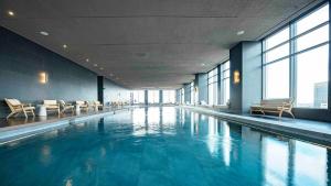 Una piscina en un edificio con sillas y ventanas. en Luxurious Master Suite with Awesome View, Jacuzzi, GYM & Balcony, en Ciudad de México
