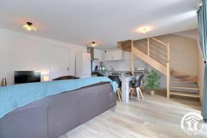a bedroom with a bed and a kitchen and a staircase at Le refuge enchante in Paimpont