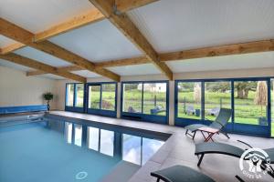 a swimming pool with a table and chairs and windows at Le refuge enchante in Paimpont