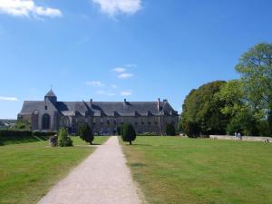 a large building with a pathway in a field at Le refuge enchante in Paimpont