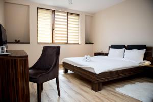 a bedroom with a bed and a desk and a chair at Luxe Stay in Târgu-Mureş