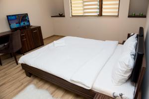 a bedroom with a bed with white sheets and a desk at Luxe Stay in Târgu-Mureş