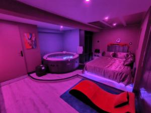 a purple bedroom with a bed and a tub at Chambre Romantique avec Spa Privé Intérieur in Rimons