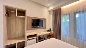 a bedroom with a desk and a tv and a bed at Baliem Resort Jimbaran in Jimbaran