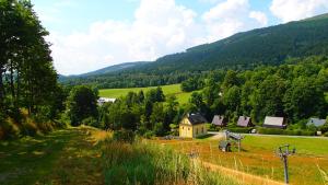 a field with a house in the middle of a mountain at Penzion Pod Zvonem in Hynčice pod Sušinou