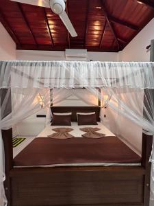 a bedroom with a bed with a mosquito net at SJ7 Guest House in Mirissa