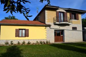 una casa gialla con portico e balcone di Al Bosco delle Api a Gallicchio