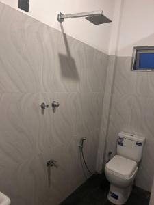 a bathroom with a white toilet and a shower at SJ7 Guest House in Mirissa
