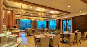 a dining room with tables and chairs and windows at New Century Manju Hotel Shanghai New International Expo Center in Shanghai