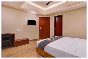 Un dormitorio con una cama, un escritorio y un televisor. en Hotel Magnus Residency Near Railway Station, en Cuttack