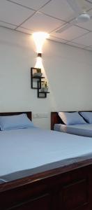 阿努拉德普勒Dewdula villa的一间设有两张床的客房,墙上有一盏灯