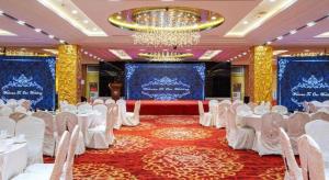 a banquet hall with white tables and chairs and a chandelier at Inzone Garlnd Hotel Zhangqiu in Jinan
