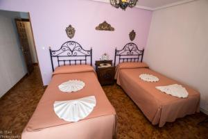 two beds in a room with pink walls at Hostal Camino de Santiago in Frómista