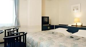 a bedroom with a bed with two chairs and a television at Hirosaki Ekimae Hotel in Hirosaki +97 photos